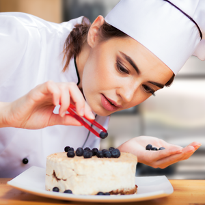 Home chef decorating a whipped cream cake with blueberries