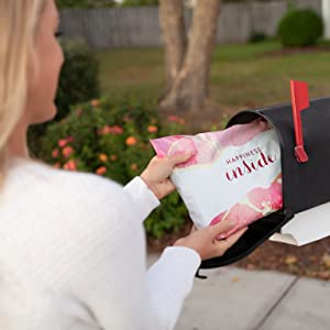 Woman pulling pink poly mailer out of mailbox.