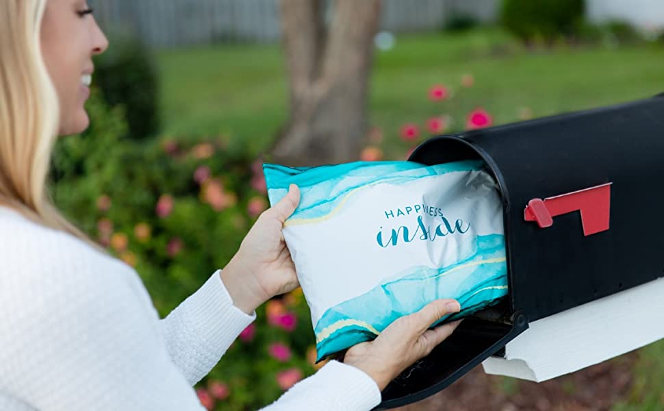 Woman removes blue poly mailers that says "Happiness Inside" from mailbox.